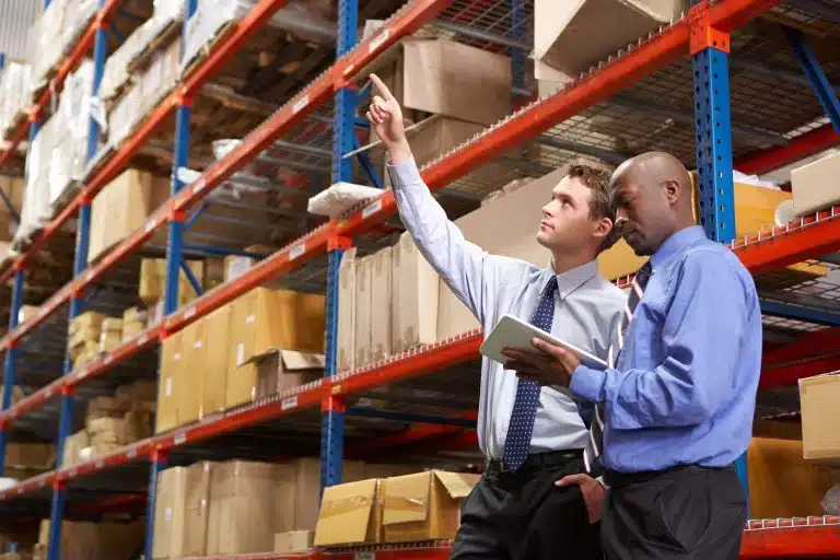 Two warehouse managers reviewing inventory on tablet in modern distribution center
