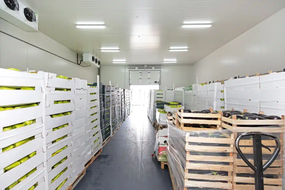 Cold storage warehouse interior with stacked produce crates and pallet jack