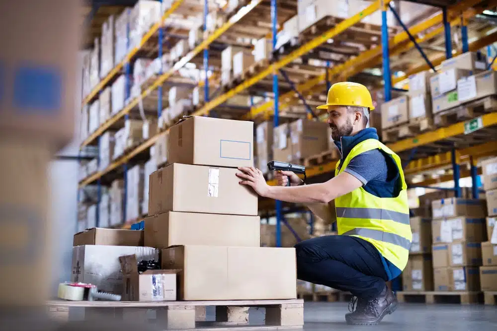 Warehouse worker scanning boxes with barcode scanner in distribution center
