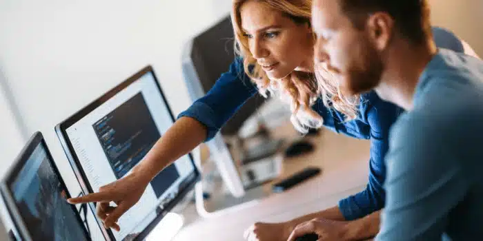 Two professionals reviewing 3PL WMS software performance data on computer screens