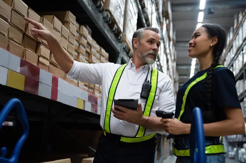 Warehouse workers using barcode scanning devices to manage inventory on storage shelves