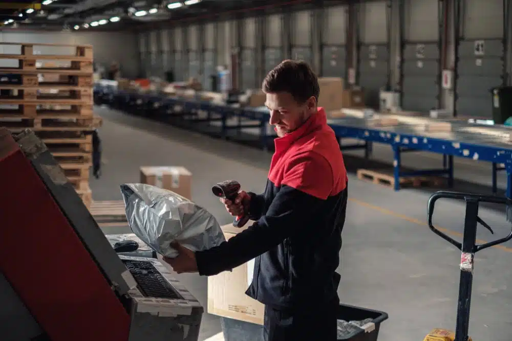 Warehouse worker scanning package with barcode scanner in shipping facility