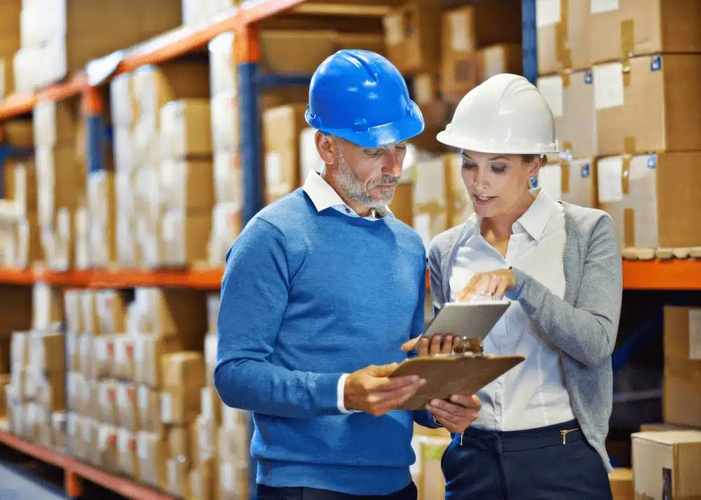 Two warehouse managers reviewing inventory data on tablets in modern distribution center