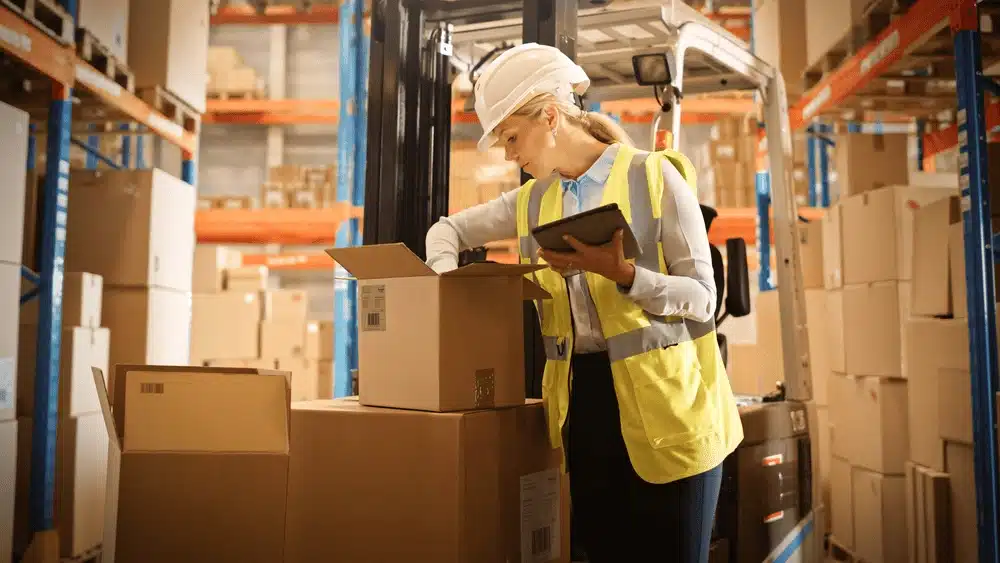 Warehouse worker in safety vest checking inventory with tablet in 3PL fulfillment center