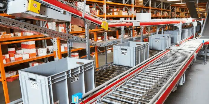 Modern warehouse conveyor system with gray bins for sustainable distribution operations