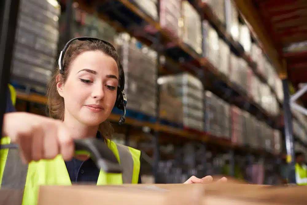 Female warehouse worker scanning barcode with handheld scanner in distribution center