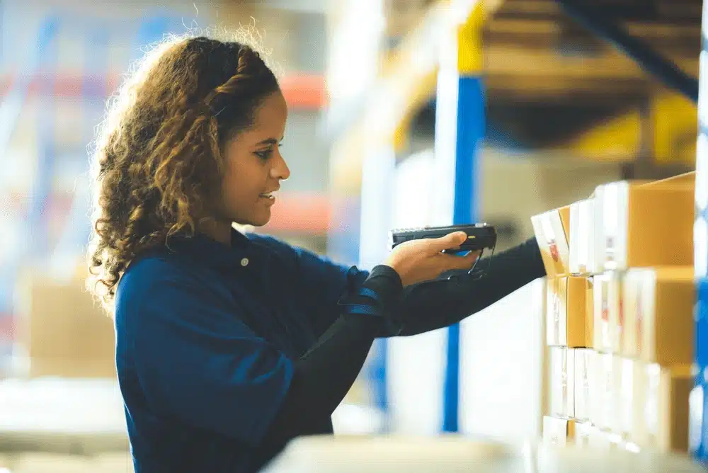 Woman scanning inventory barcode in warehouse with handheld scanner device