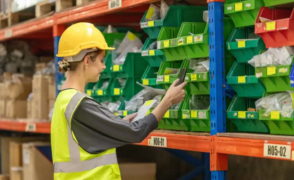 Warehouse worker scanning rack labels with barcode scanner for inventory management
