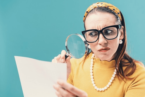 woman looking at paper with a magnifying glass