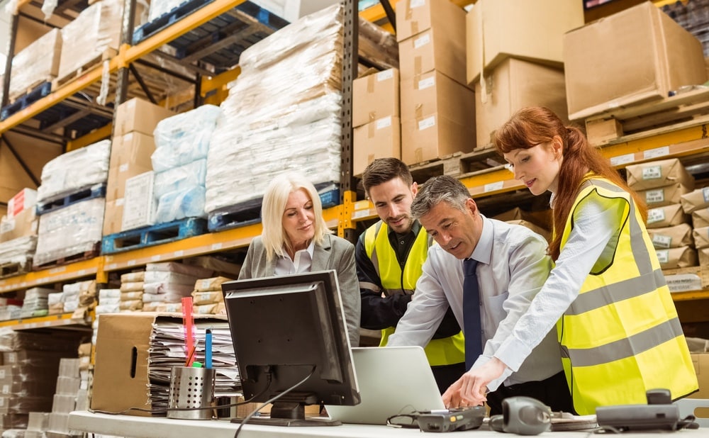 Warehouse managers and worker talking in a large warehouse