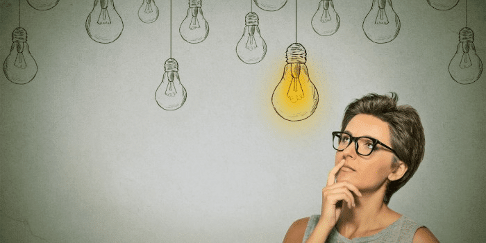 woman surrounded by lightbulbs, one is lit up