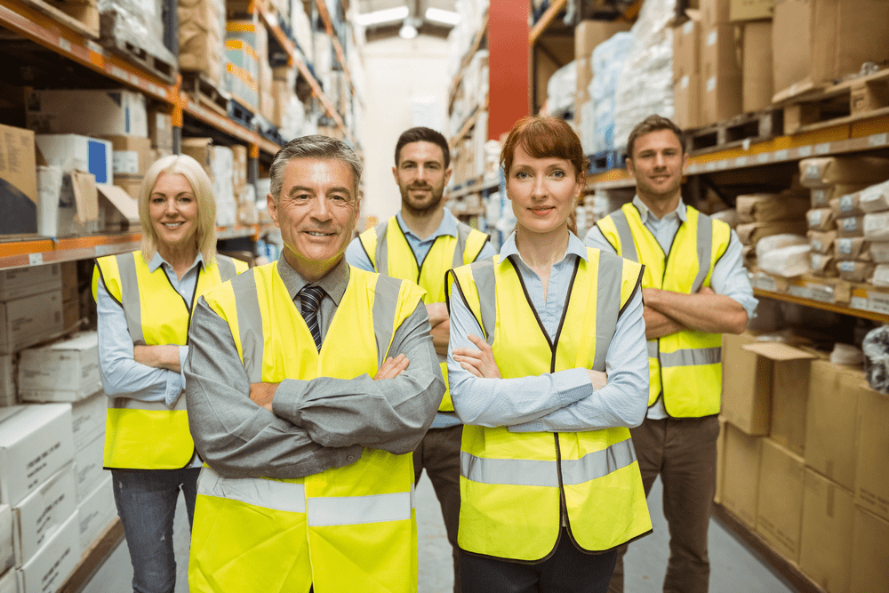 warehouse workers standing in warehouse with arms crossed