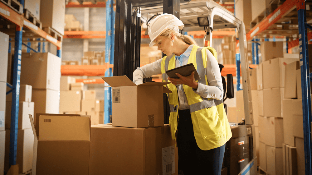 warehouse worker look in a box holding a tablet