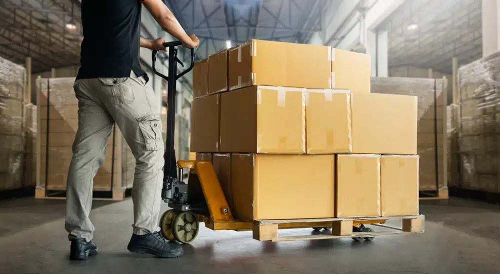 warehouse worker moving pallet of boxes