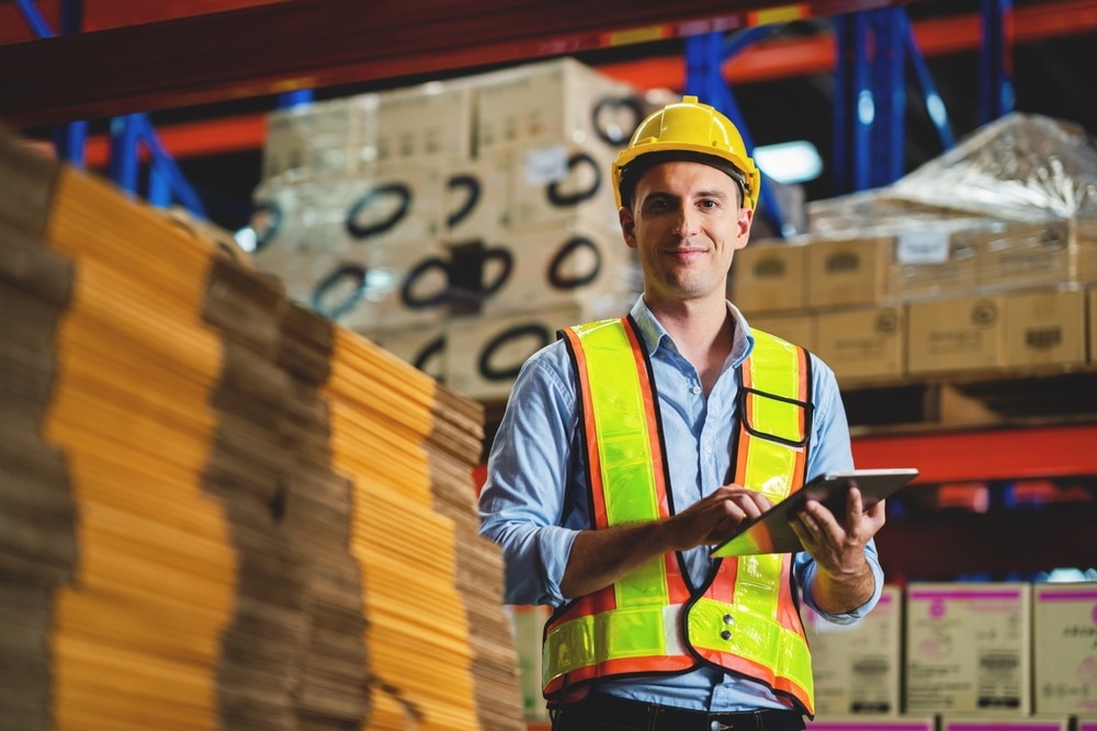 warehouse worker holding inventory management software tablet