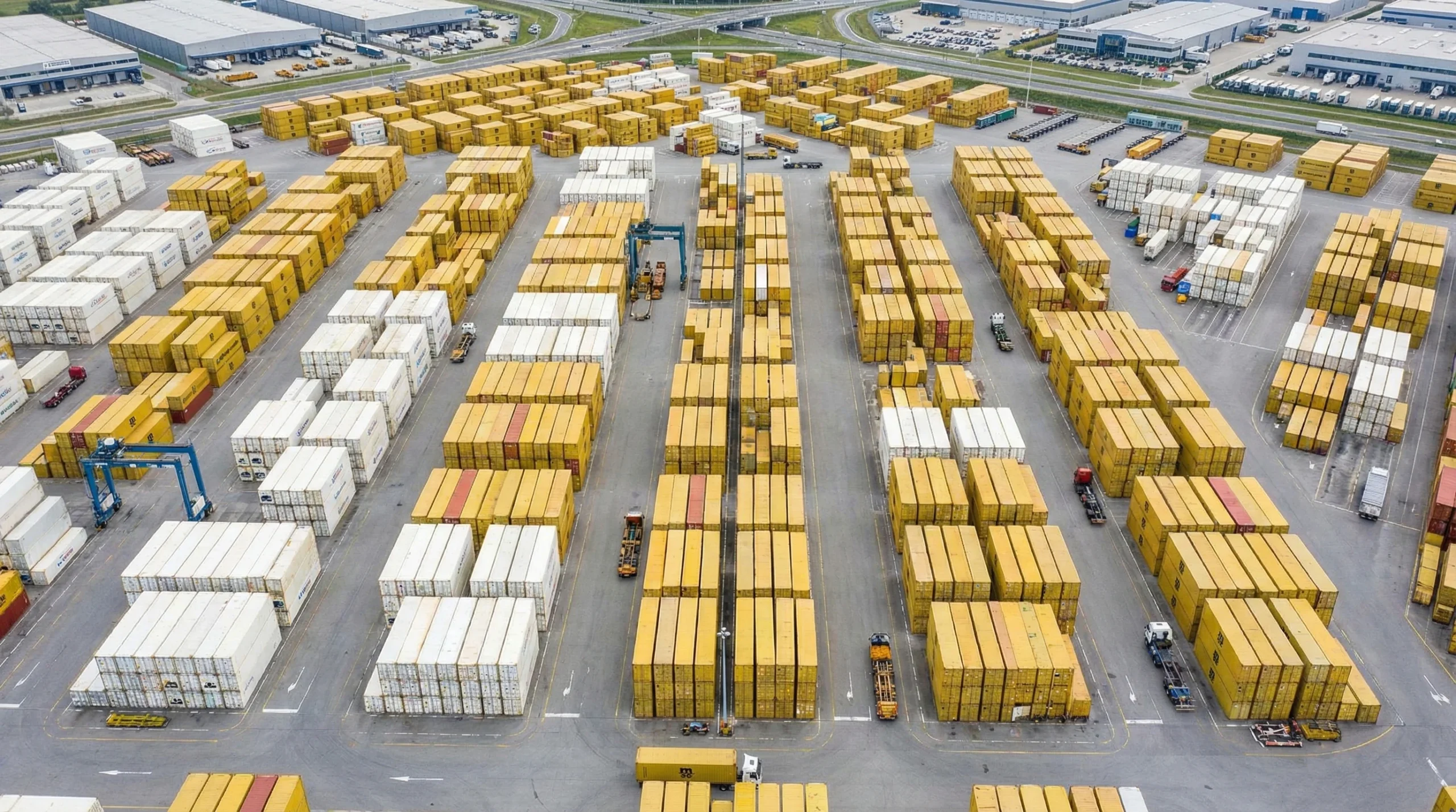 Aerial view of organized warehouse yard with yellow and white shipping containers