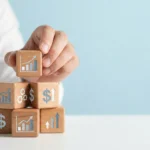 Hand stacking wooden blocks with business growth and KPI icons on light blue background
