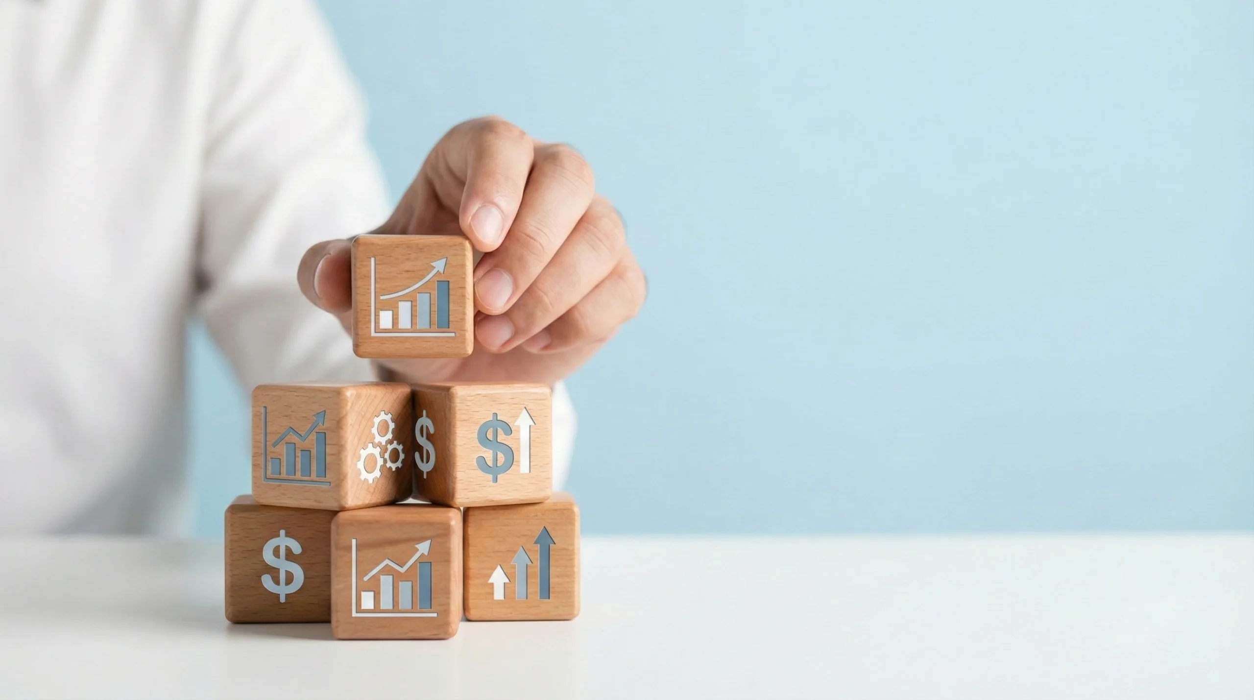 Hand stacking wooden blocks with business growth and KPI icons on light blue background