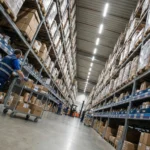 Warehouse aisle with tall shelves and worker.